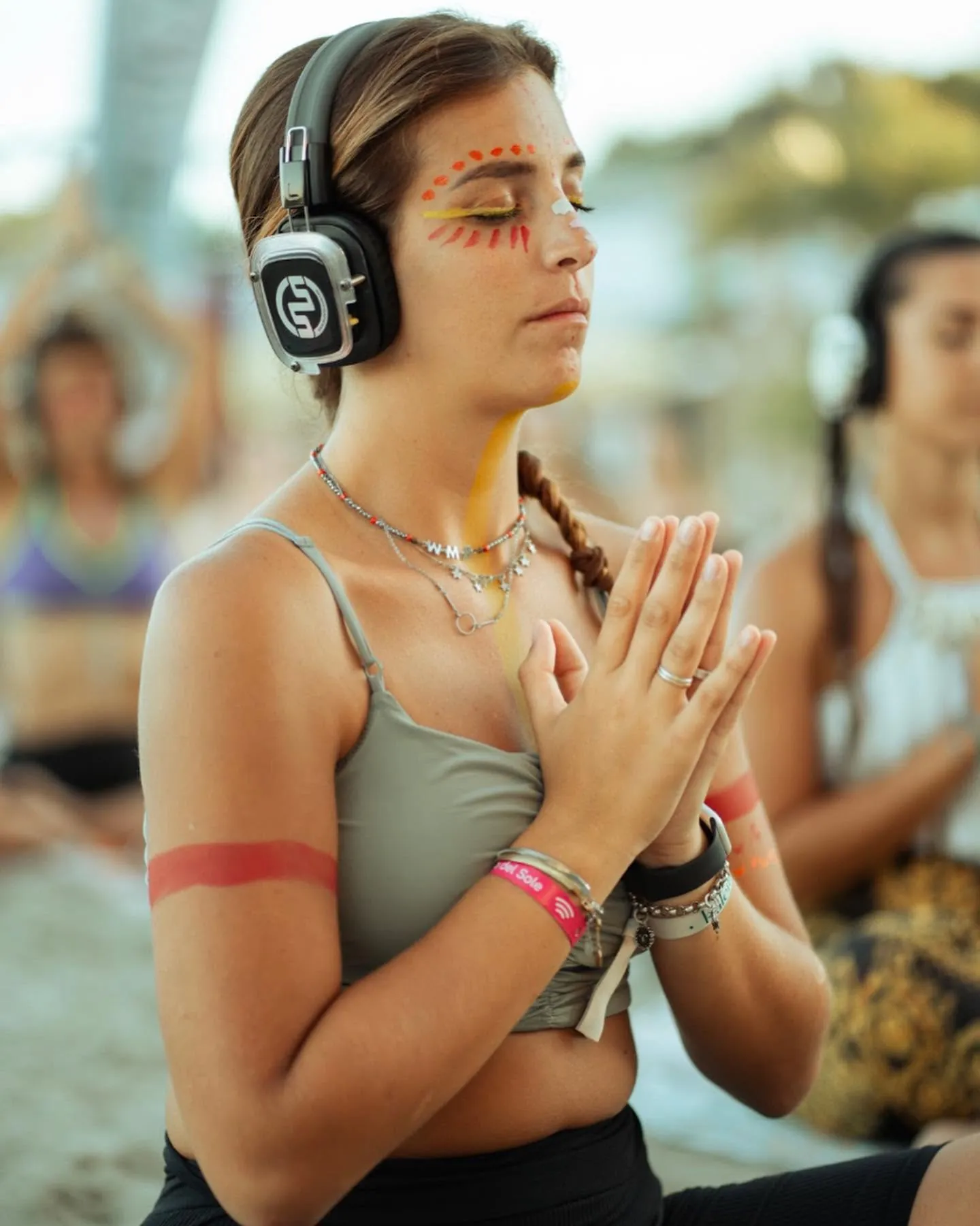 Participant with face paint, hands together, during a festival session