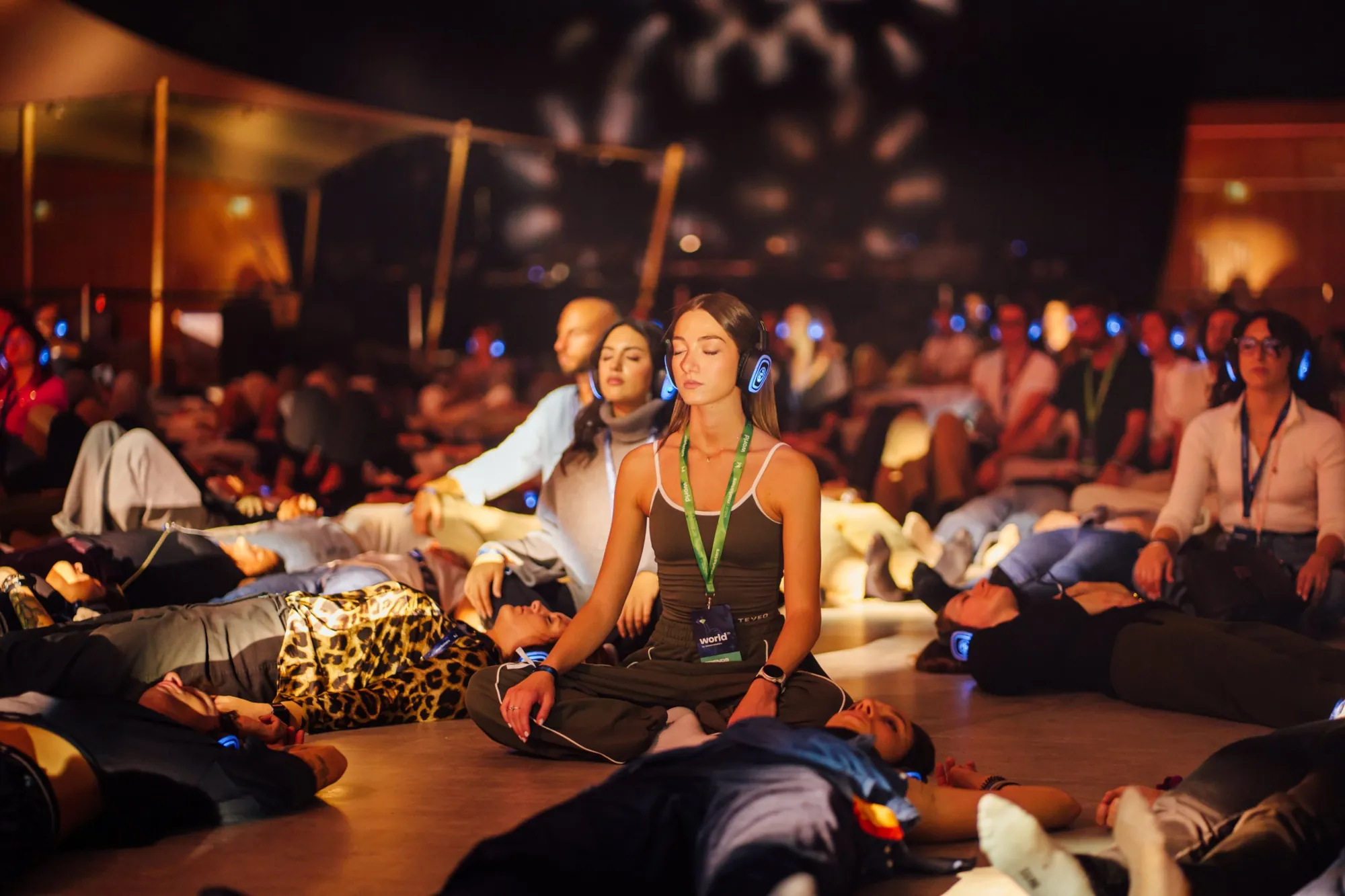 Group meditation at an event, with blue-lit wireless headphones