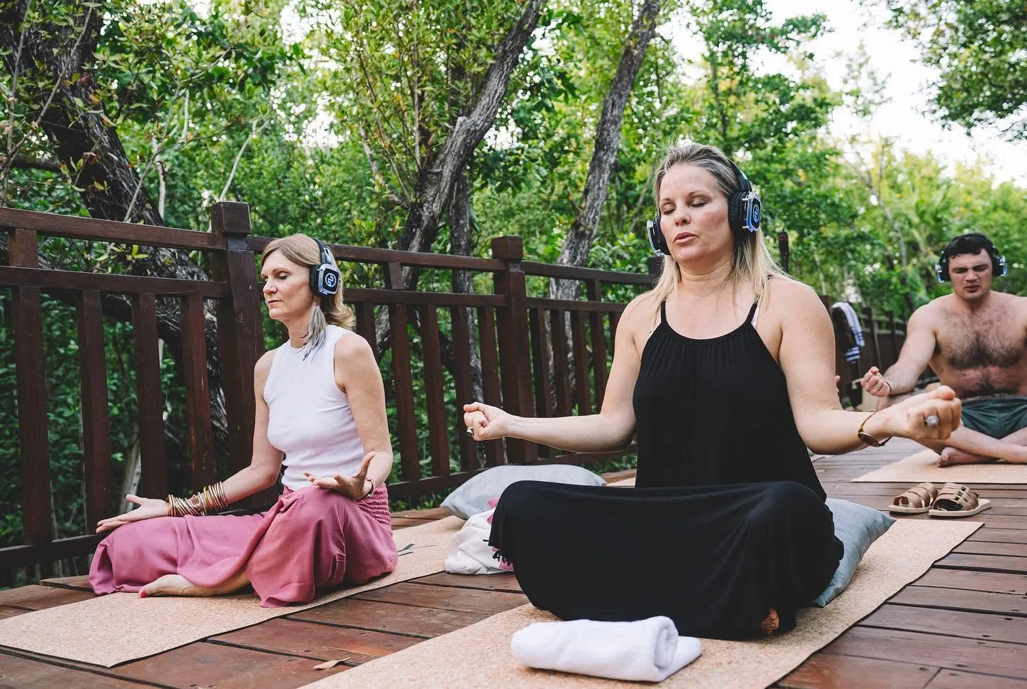 Meditation on a wooden deck among the trees, with wireless headphones